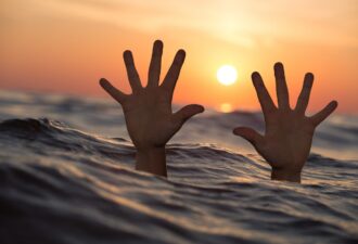Руки, що виступають з води під час заходу сонця, символізують відчай і потребу у допомозі.