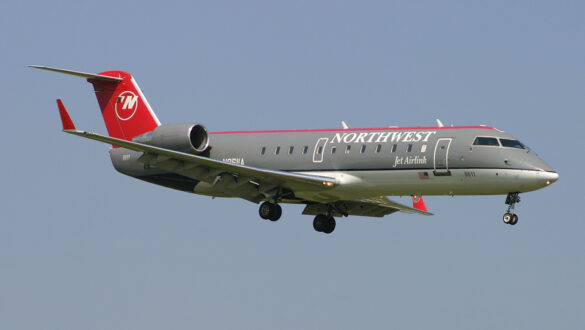 Літак Bombardier CRJ-200 компанії Northwest Jet Airlink на підході до посадки з ясним небом на фоні.