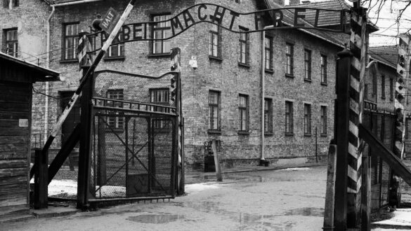 Ворота історичного концентраційного табору, з написом про працю, сріблястю проходу на фоні старих brick будівель, що відображає важливу частину історії.
