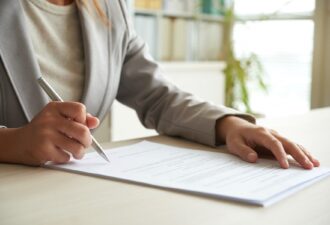 Обрізаний середній план невпізнаної жінки, яка підписує документ