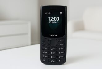 Класичний мобільний телефон Nokia чорного кольору стоїть на білому столі в світлій кімнаті; на екрані видно час 12:00 та дату 30.06.2023.