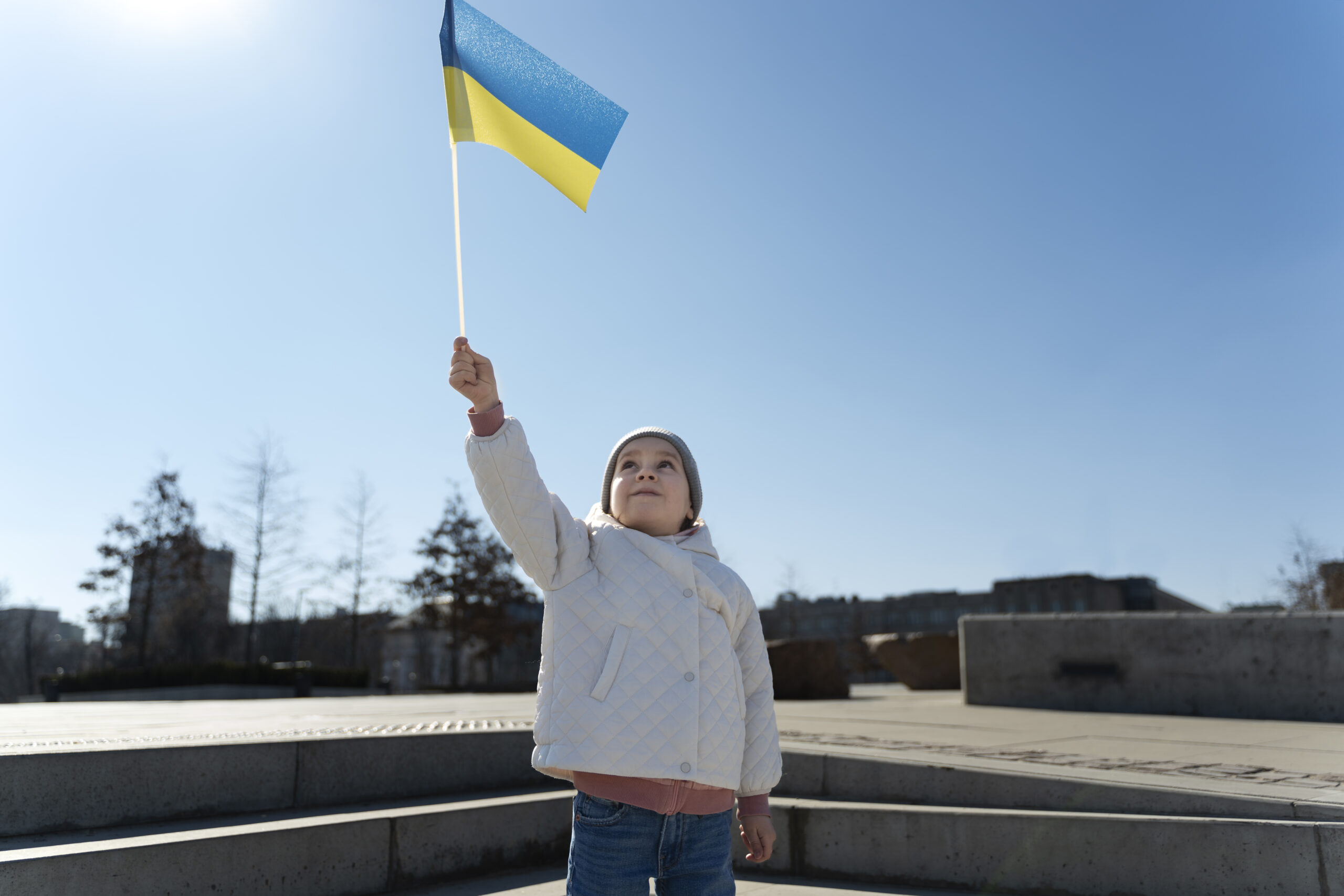 Дитина з українським прапором у руці на вулиці в сонячний день