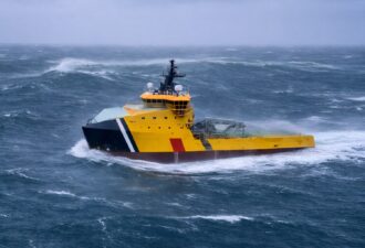 Бурхливе море і жовто-чорне рятувальне судно з хвилерізним носом, що прорізає великі хвилі під похмурим небом.