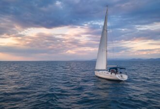 Спокійне відкрите море з вітрильною яхтою під драматичним небом — ілюстрація того, як у глибокій воді хвилі залишаються майже непомітними навіть за потенційно небезпечних умов.